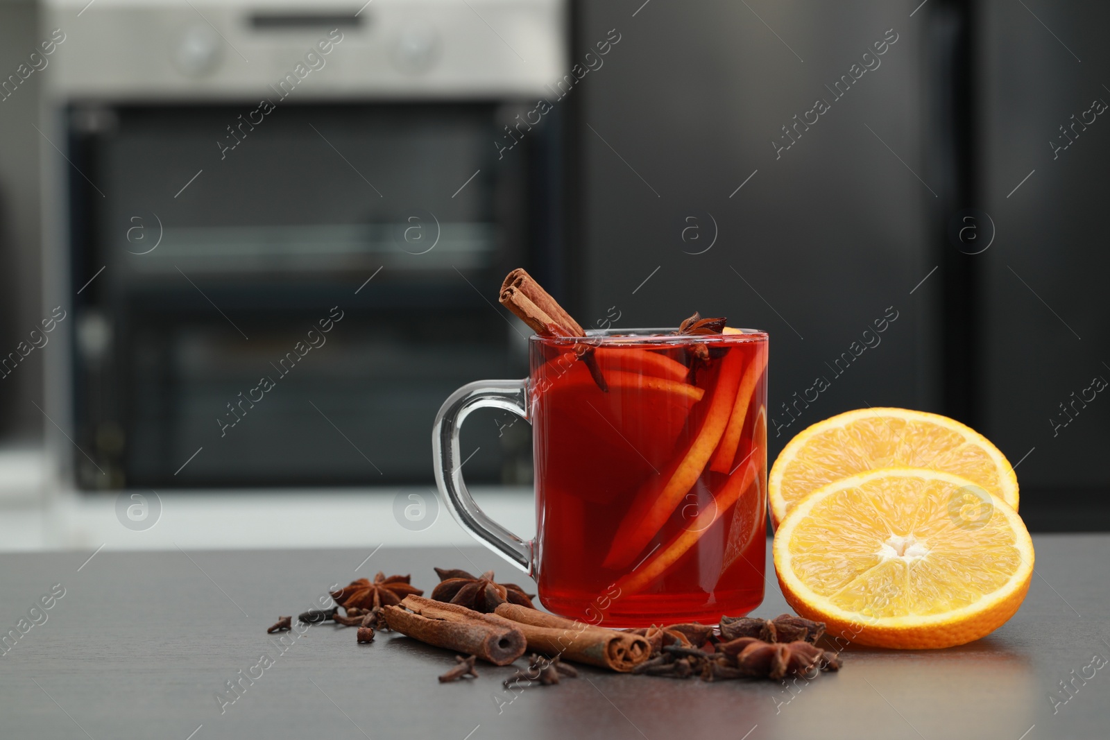 Photo of Aromatic punch drink and ingredients on grey table in kitchen. Space for text