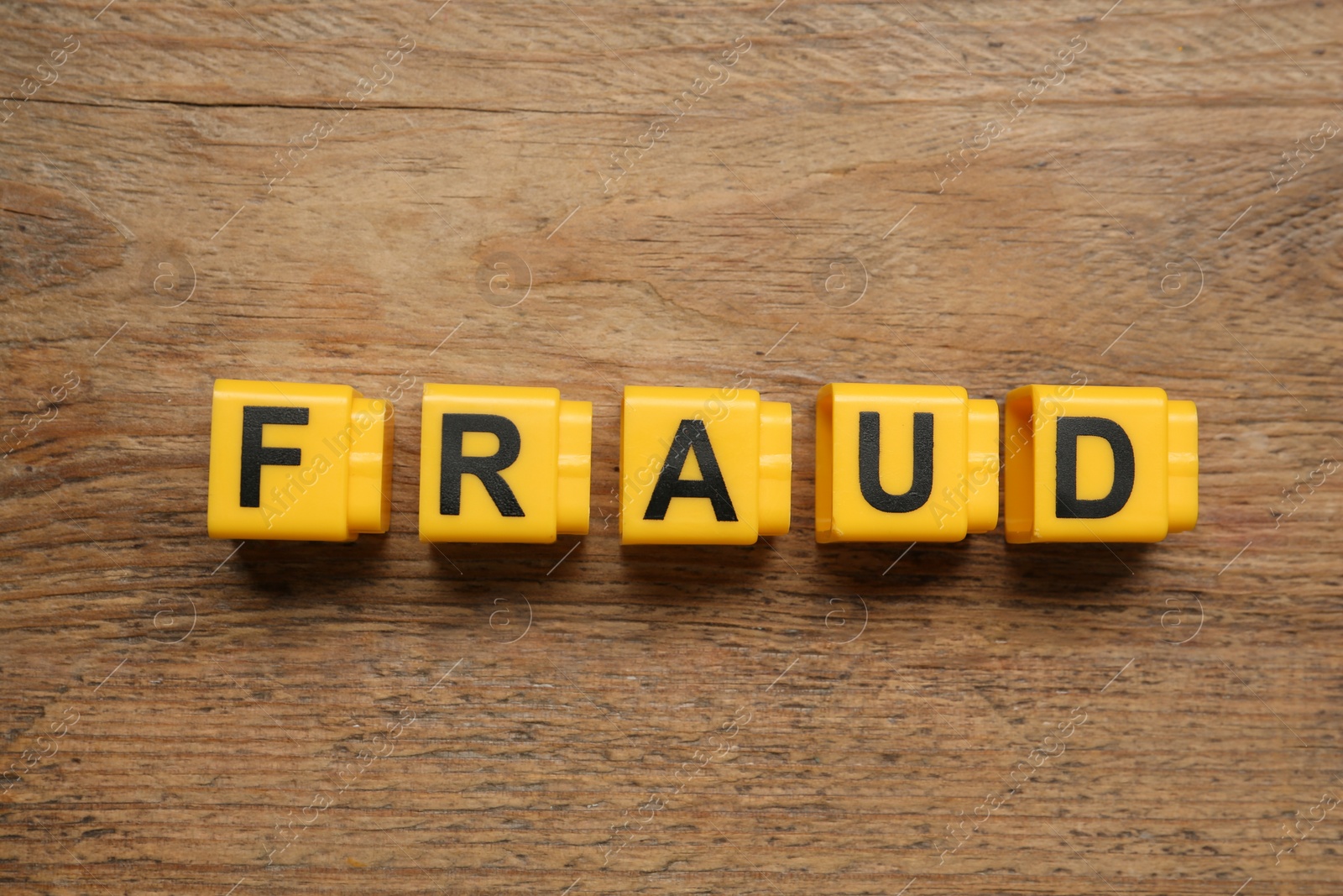 Photo of Word Fraud of yellow cubes with letters on wooden background, flat lay
