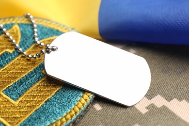 Military ID tag, patch and Ukrainian flag on pixel camouflage, closeup