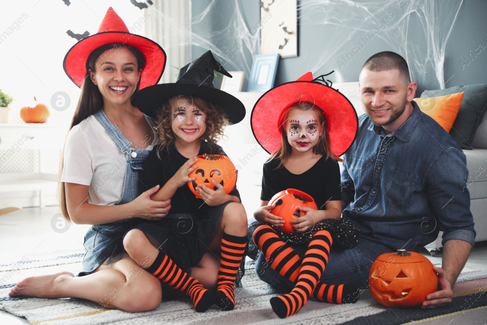 Photo of Happy family with Halloween candy buckets and pumpkin head jack lantern at home