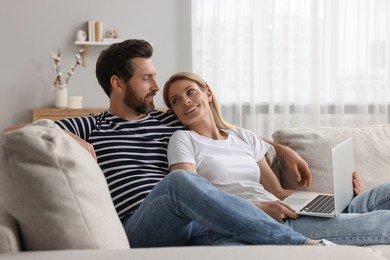 Photo of Happy couple with laptop on sofa at home