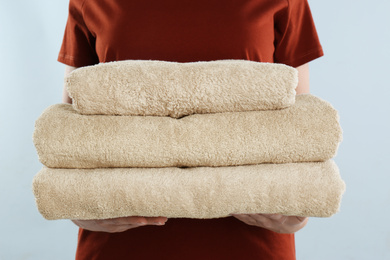 Photo of Woman holding fresh towels on light blue background, closeup