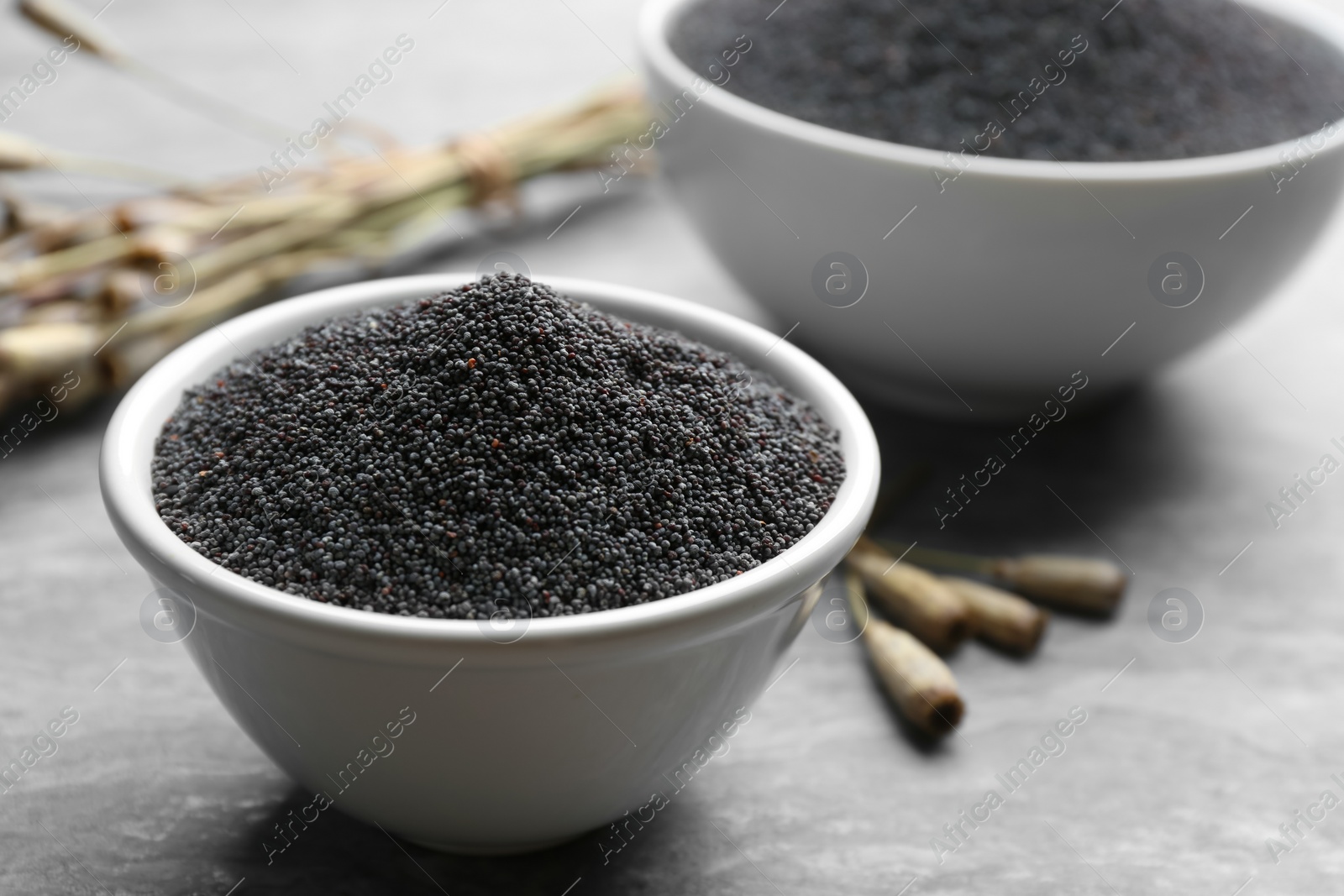 Photo of Poppy seeds in bowl on grey table