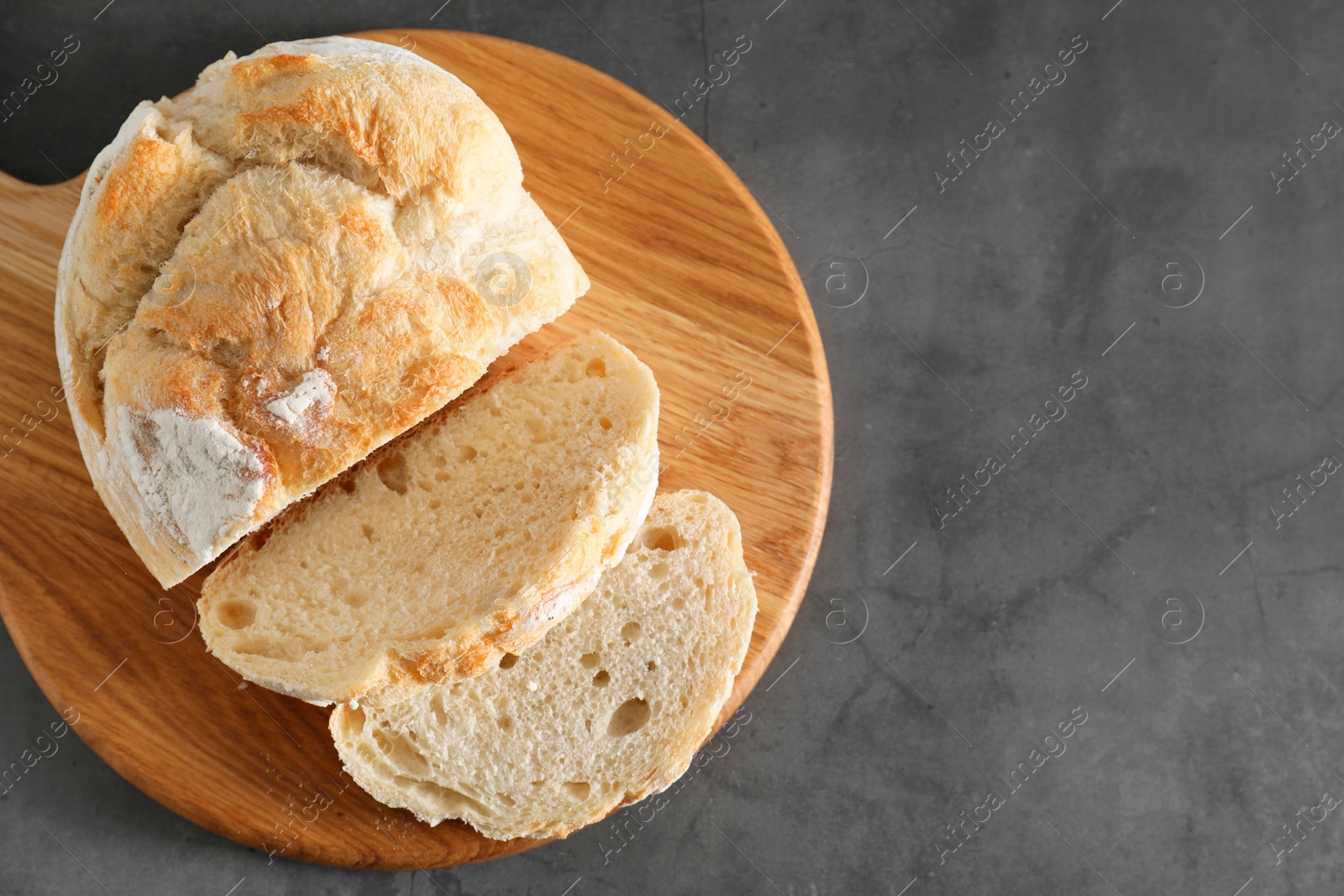 Photo of Freshly baked cut sourdough bread on grey table, top view. Space for text