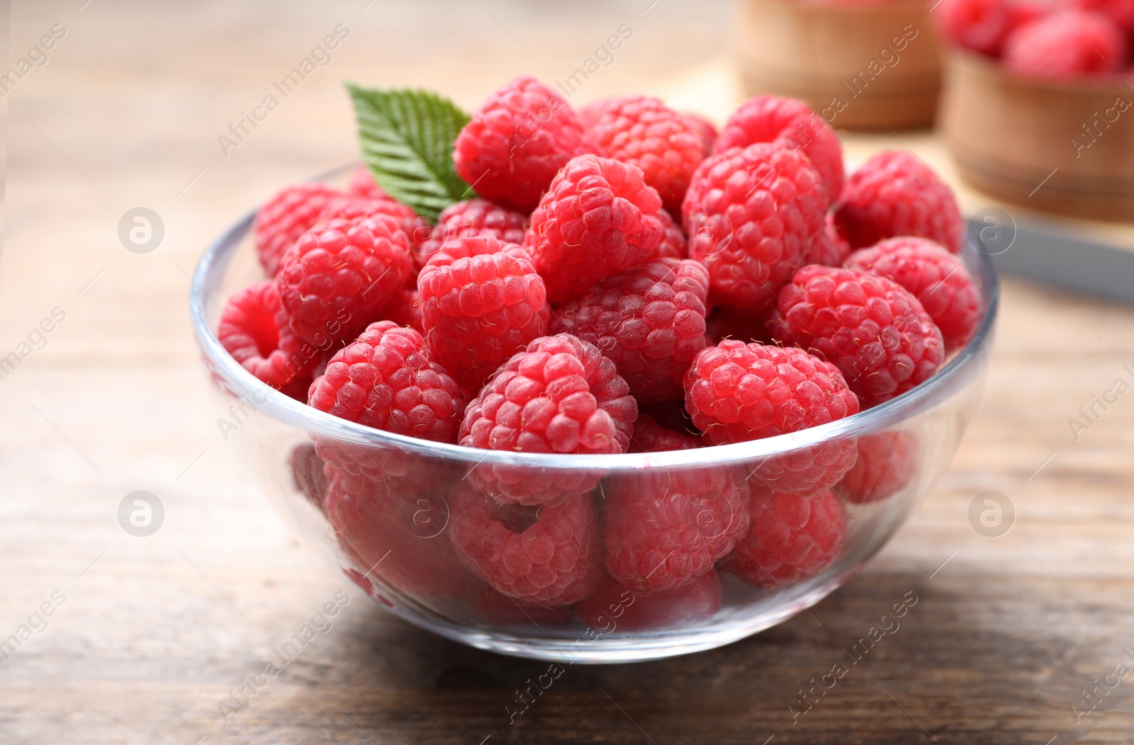 Photo of Delicious fresh ripe raspberries in bowl on wooden table, closeup