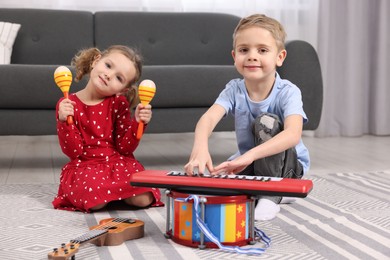 Little children playing toy musical instruments at home