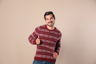 Portrait of happy man in Christmas sweater on beige background