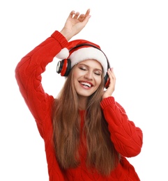 Young woman in Santa hat listening to Christmas music on white background