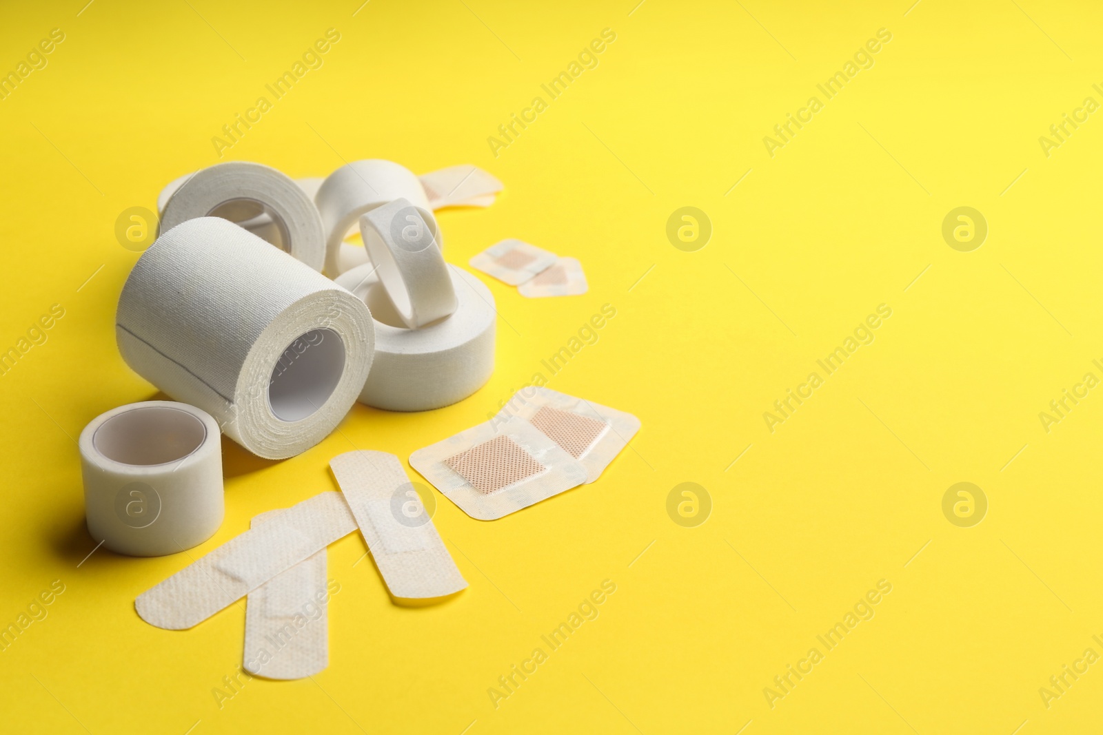 Photo of Different types of sticking plasters on yellow background. Space for text