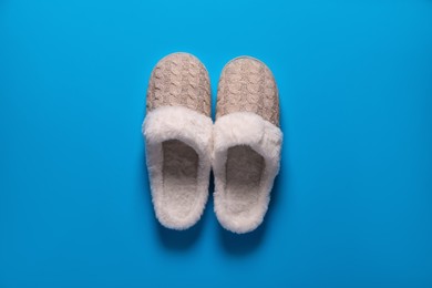 Photo of Pair of beautiful soft slippers on light blue background, top view