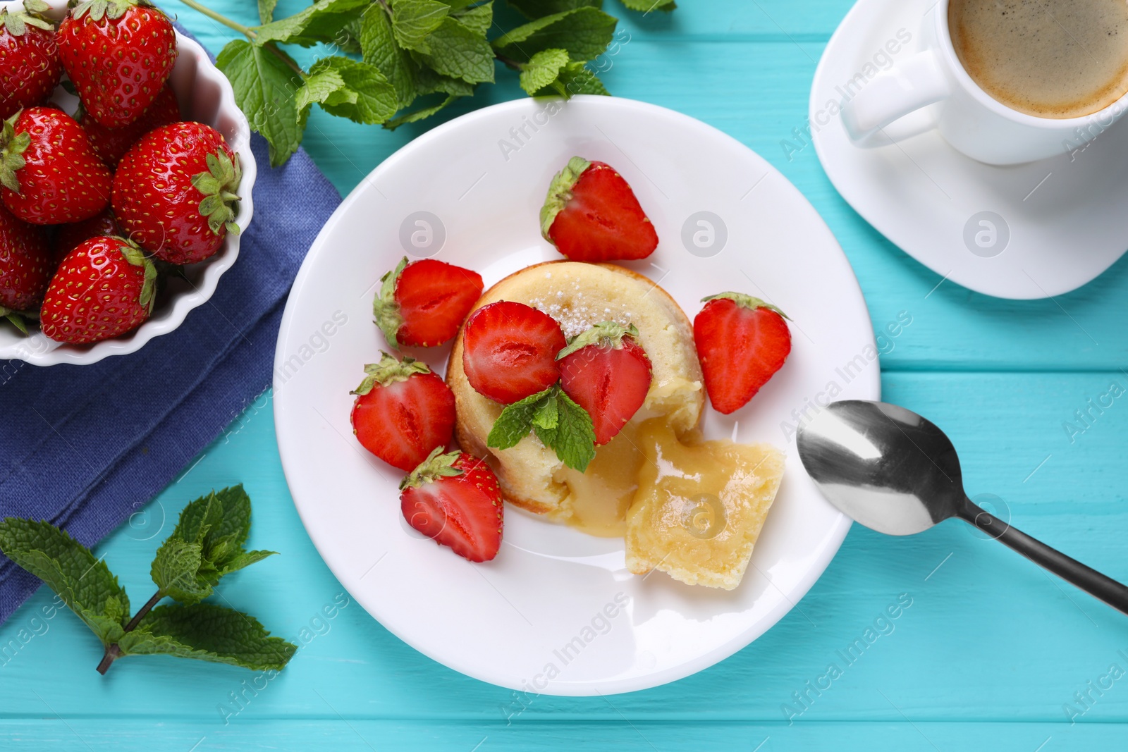 Photo of Tasty vanilla fondant with white chocolate, strawberries and cup of coffee on light blue wooden table, flat lay