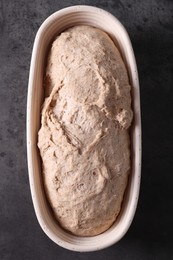 Photo of Fresh sourdough in proofing basket on grey table, top view