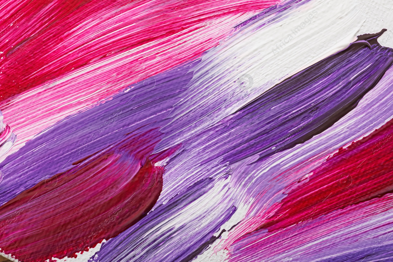 Photo of Beautiful strokes of bright oil paints on white canvas as background, closeup