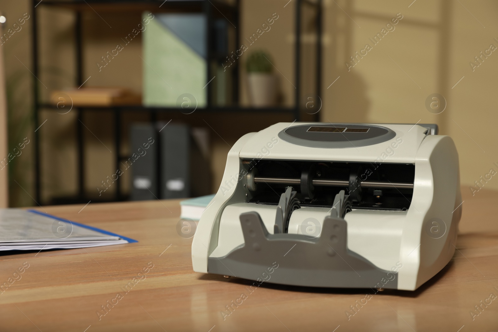 Photo of Modern banknote counter on wooden table indoors. Space for text