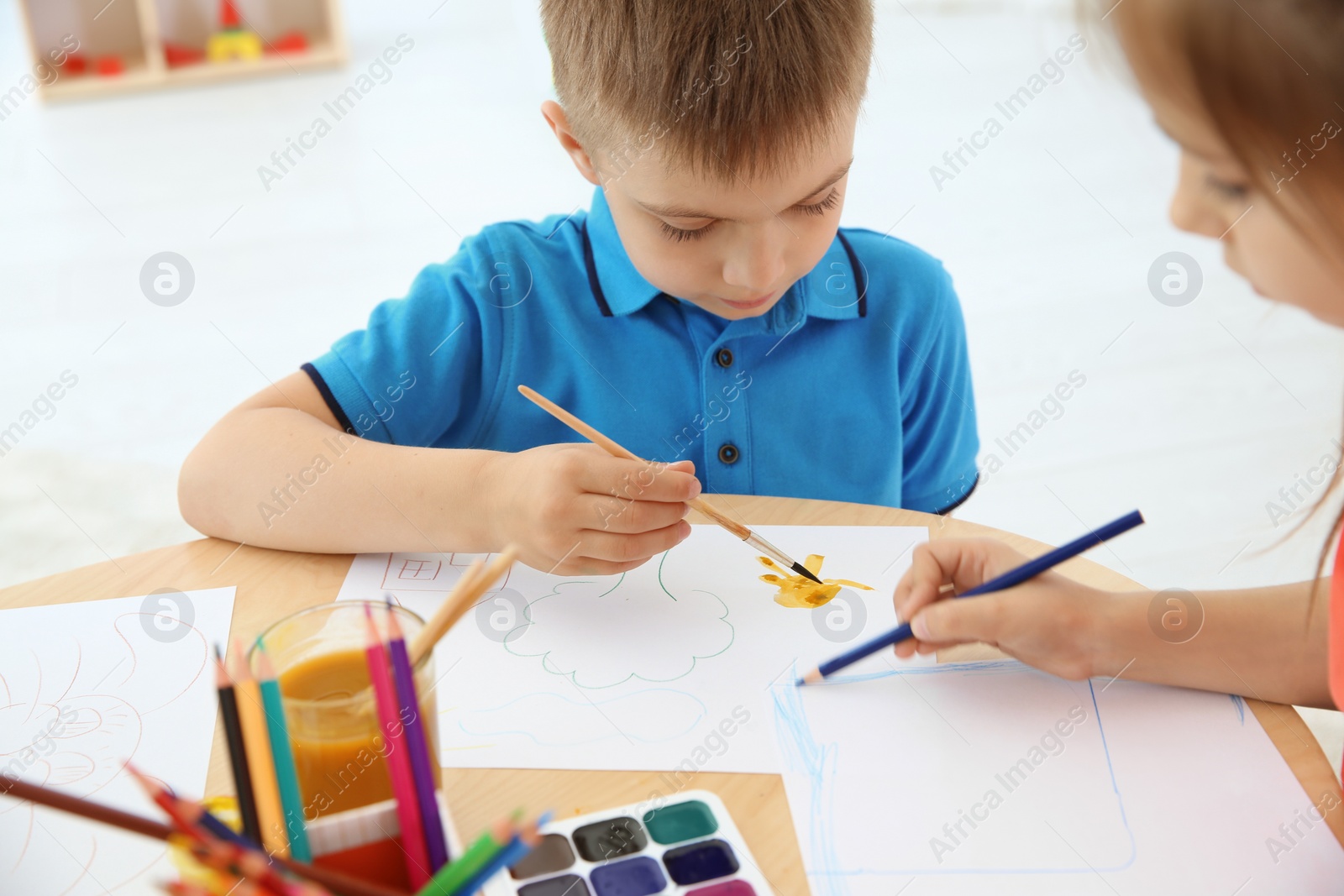 Photo of Cute little children painting at table in playing room