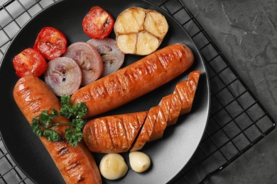 Delicious grilled sausages and vegetables on grey table, top view