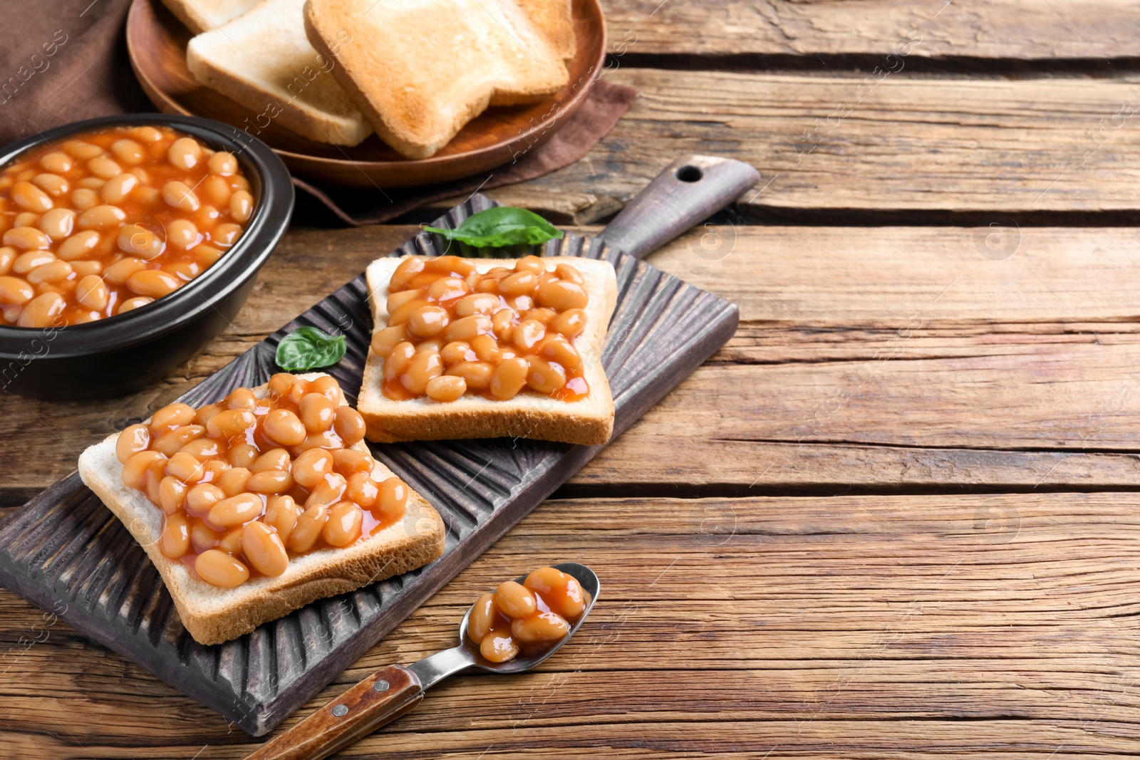 Photo of Toasts with delicious canned beans on wooden table, space for text