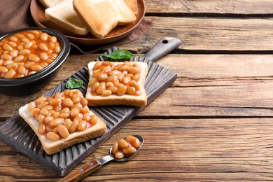 Photo of Toasts with delicious canned beans on wooden table, space for text