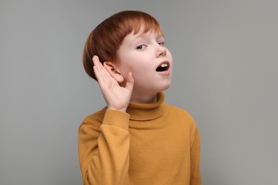Photo of Little boy with hearing problem on grey background