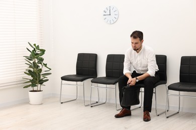 Photo of Man sitting on chair and waiting for job interview indoors