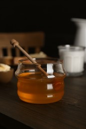 Photo of Jar with honey, milk, bread and butter on wooden table