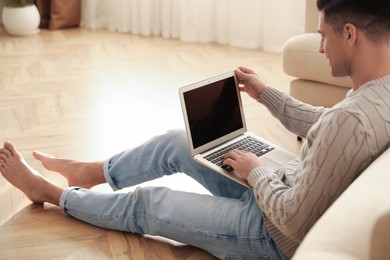 Man with laptop sitting on warm floor in living room. Heating system