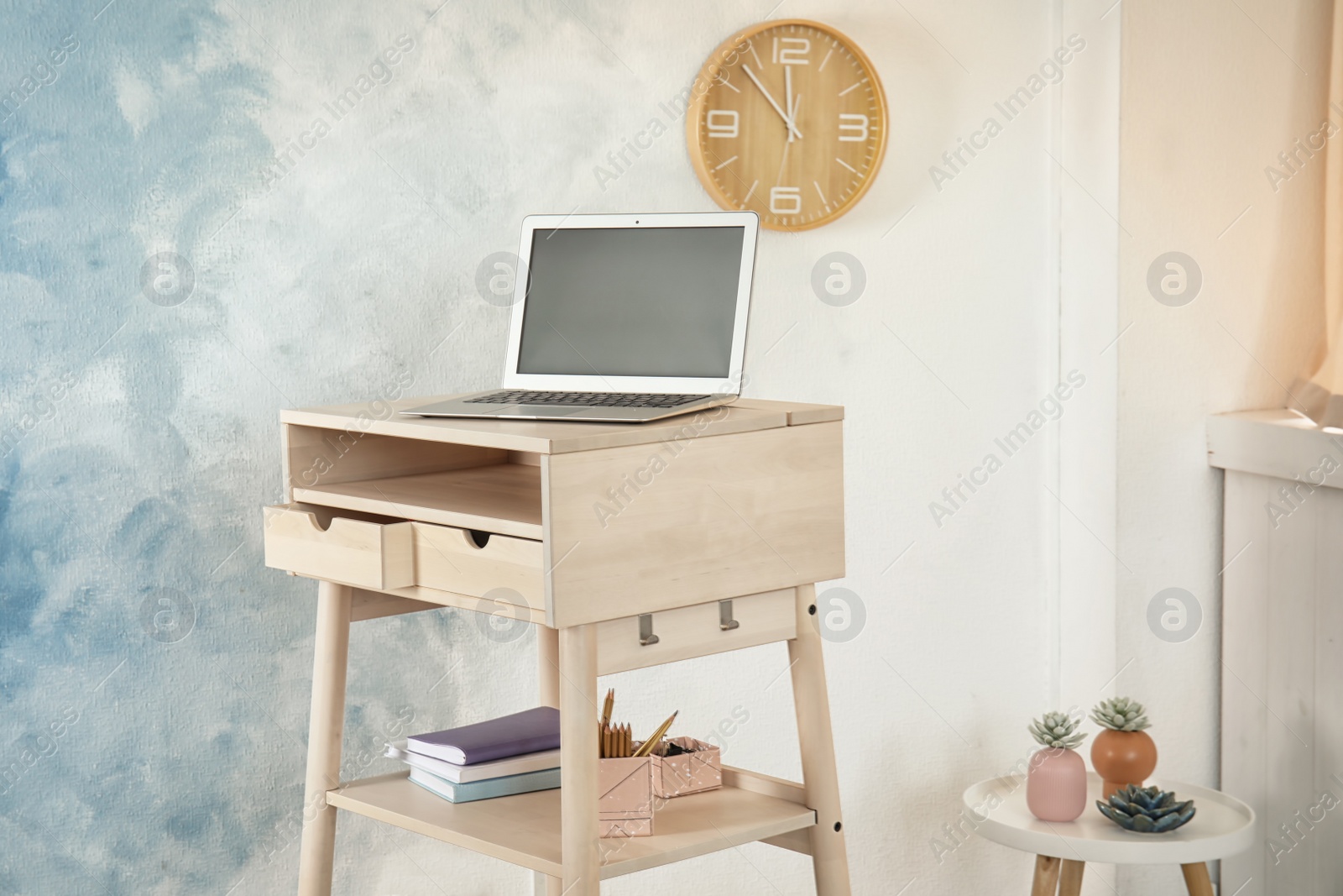 Photo of High wooden table with laptop as stand up workplace in modern interior