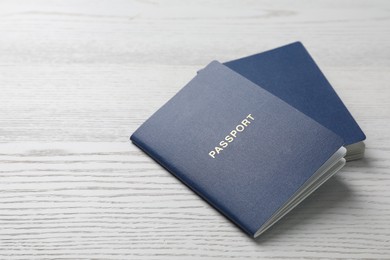 Photo of Blank blue passports on white wooden table, closeup. Space for text
