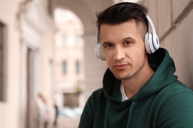 Photo of Portrait of handsome young man with headphones listening to music outdoors. Space for text