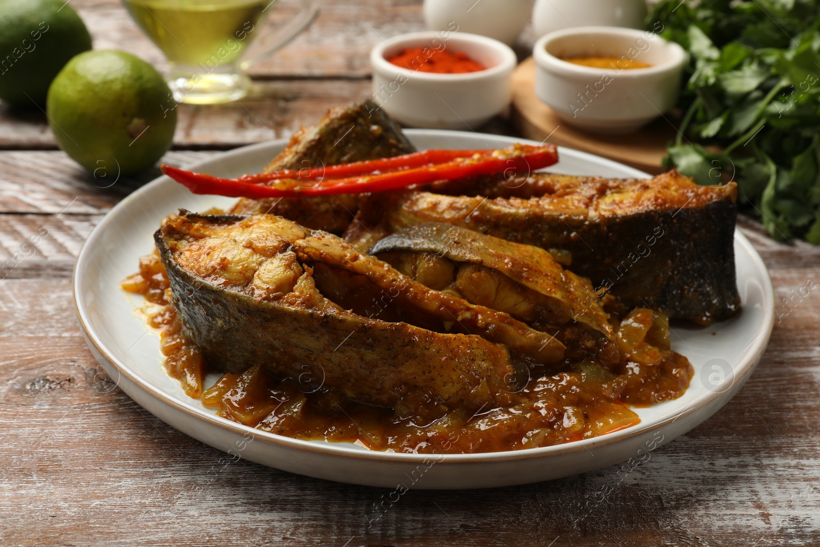 Photo of Tasty Indian fish curry on wooden table, closeup