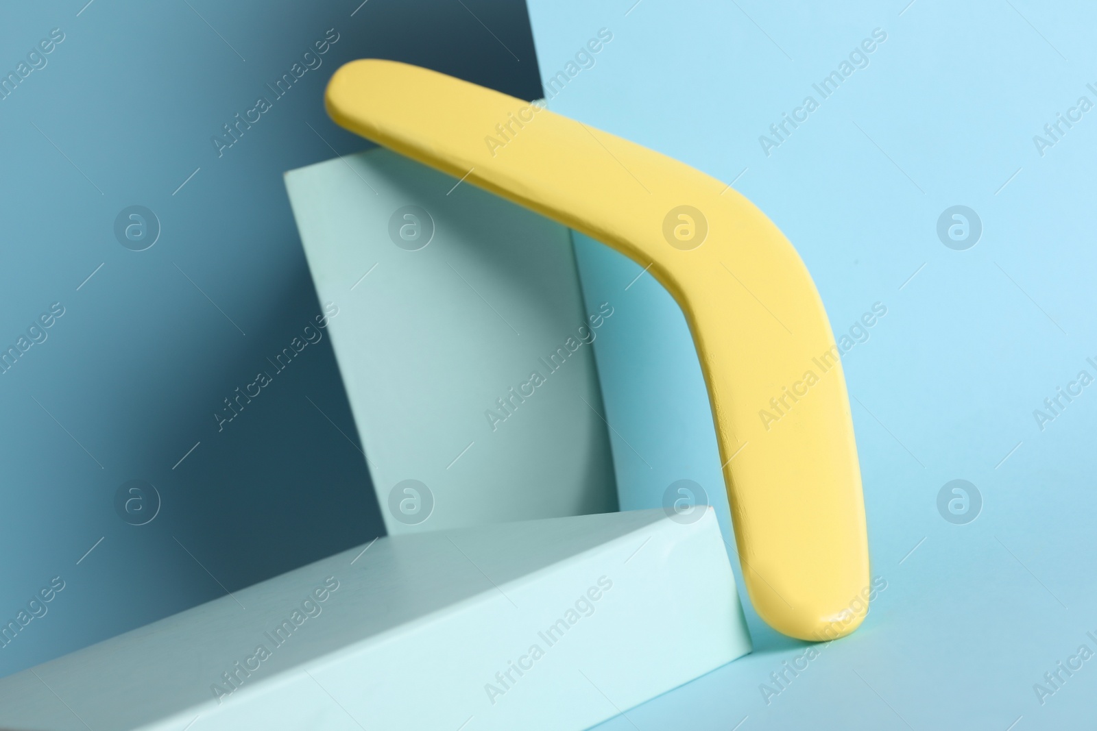 Photo of Creative composition with yellow wooden boomerang on turquoise background