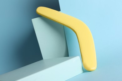 Photo of Creative composition with yellow wooden boomerang on turquoise background
