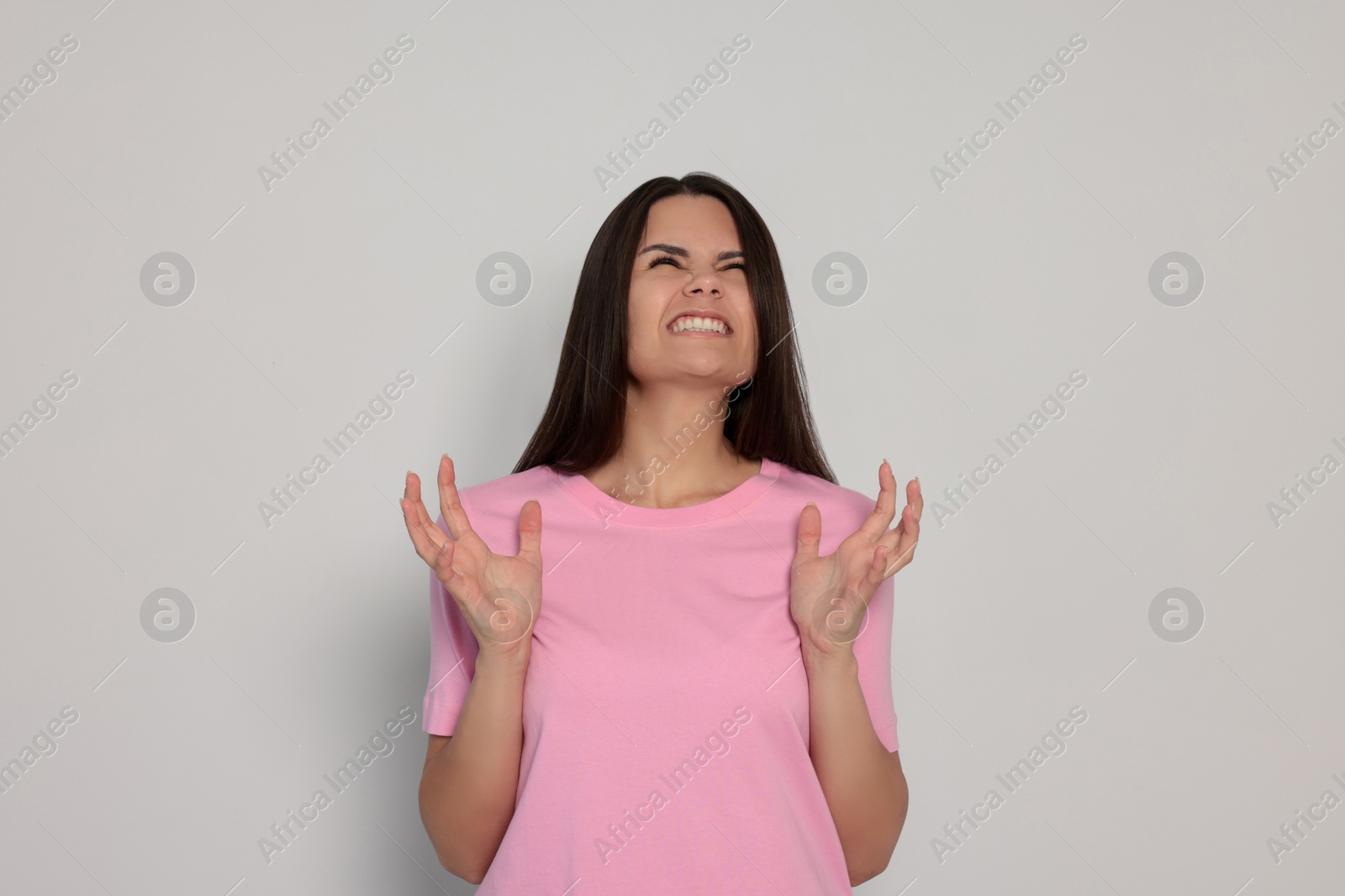 Photo of Emotional young woman on light grey background. Aggression concept