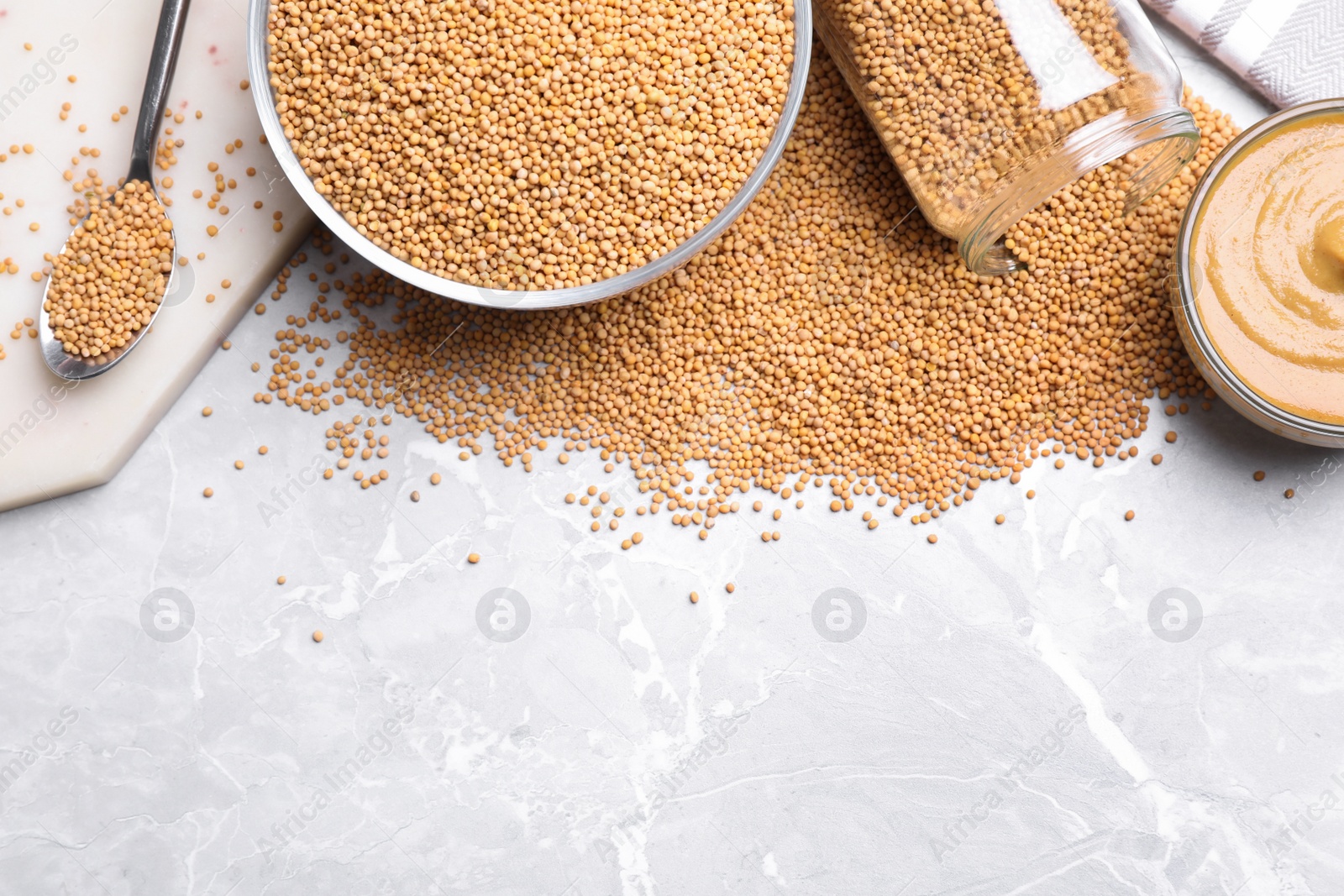 Photo of Mustard seeds on light grey table, flat lay. Space for text