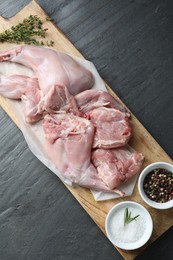 Photo of Fresh raw rabbit meat and spices on black table, top view