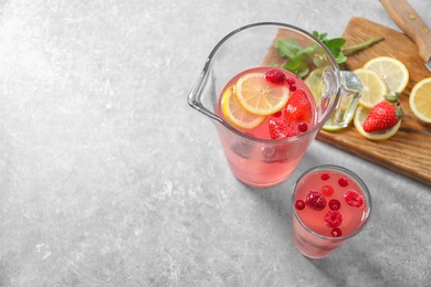 Jug and glass of fresh lemonade with berries on table