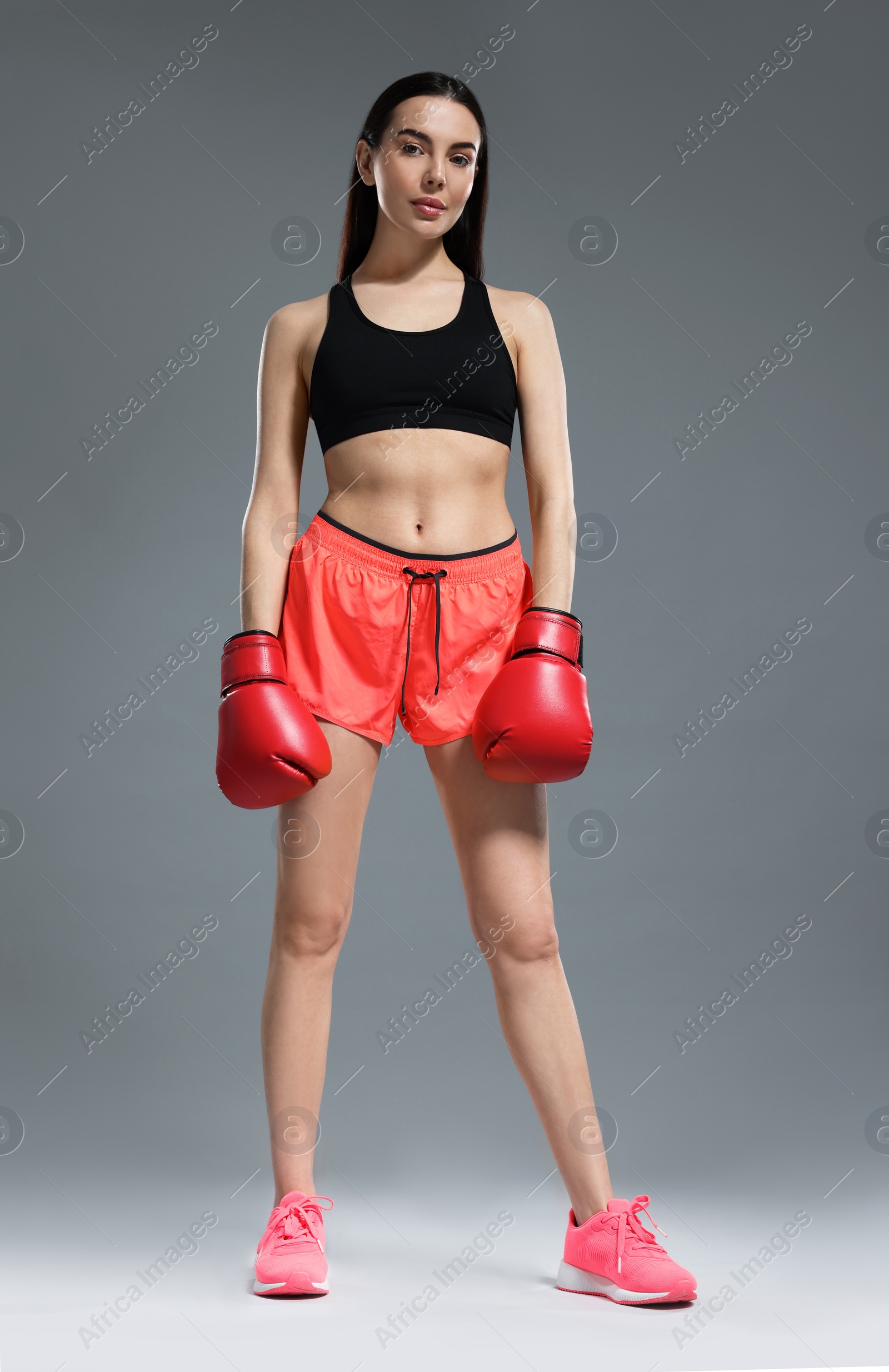 Photo of Beautiful woman in boxing gloves on grey background