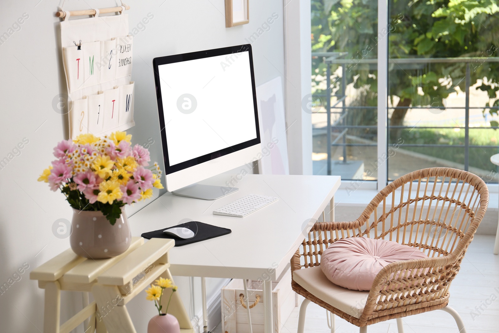 Photo of Comfortable workplace with modern computer and flowers in room. Interior design