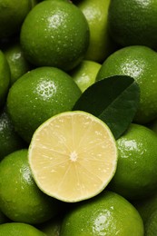 Photo of Fresh limes and leaf with water drops as background, top view