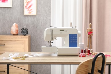 Photo of White sewing machine, cloth, craft accessories and mannequin on wooden table indoors