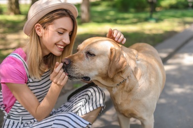 Photo of Young woman and her dog spending time together outdoors. Pet care