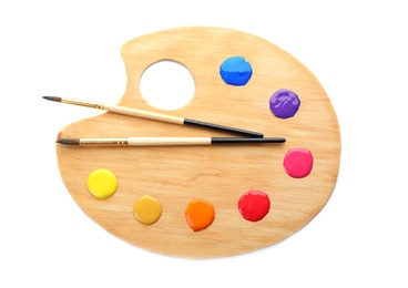 Photo of Palette with paints and brushes on white background, top view