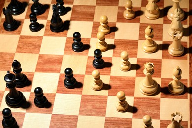 Photo of Wooden chessboard with game pieces, above view