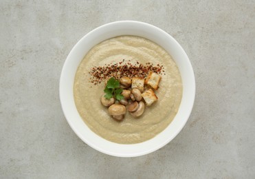 Photo of Delicious cream soup with mushrooms and croutons on beige textured table, top view