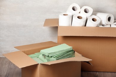 Photo of Cardboard boxes with paper towels and napkins on floor indoors