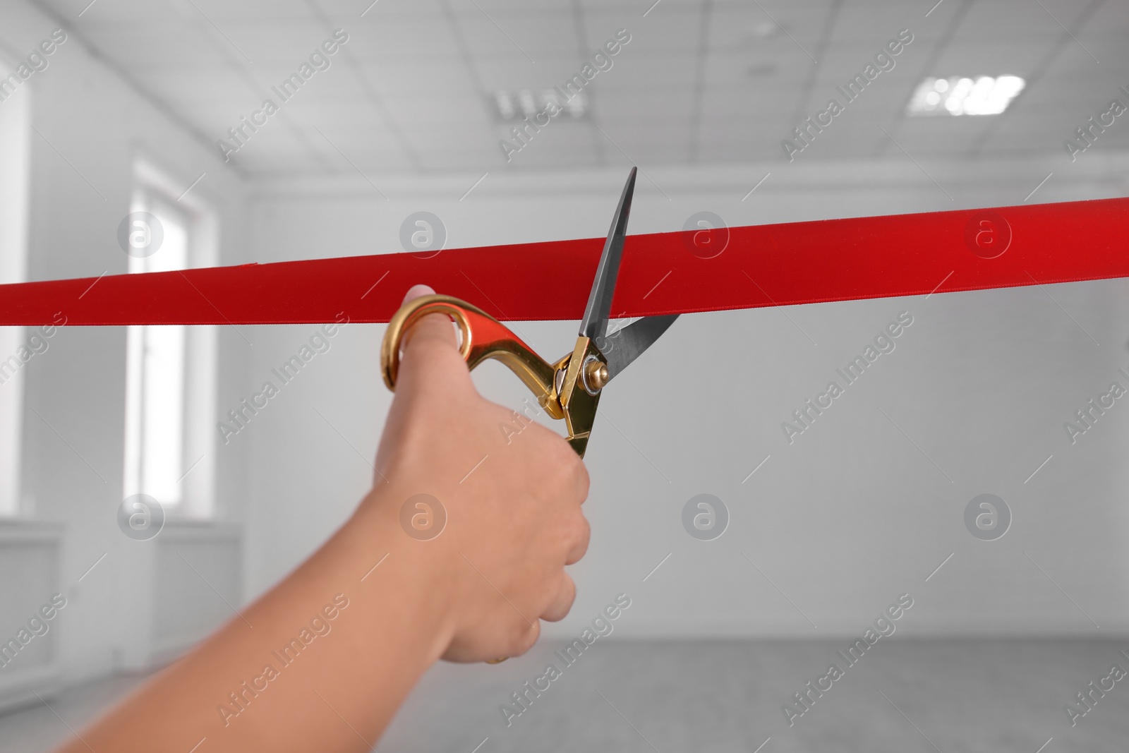 Photo of Woman cutting red ribbon on blurred background. Festive ceremony