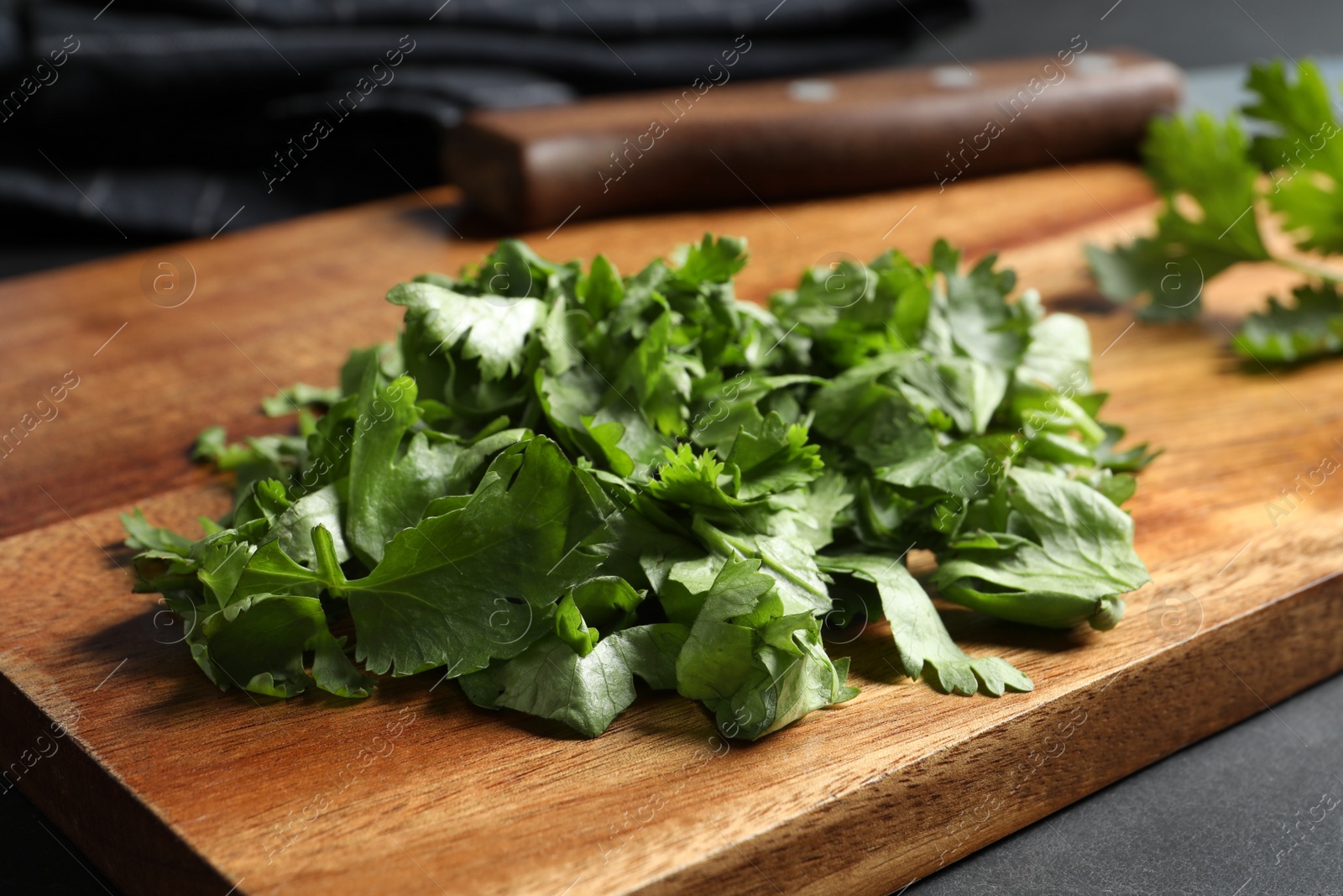 Photo of Cut fresh green cilantro on black table, closeup