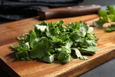 Photo of Cut fresh green cilantro on black table, closeup