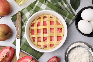Flat lay composition with raw apple pie and ingredients on light grey textured table