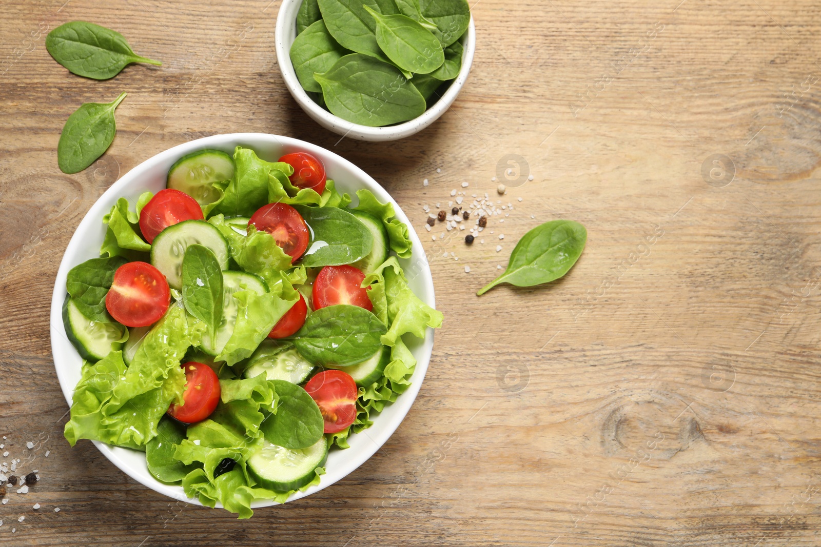 Photo of Delicious vegetable salad and bowl of spinach on wooden table, flat lay. Space for text